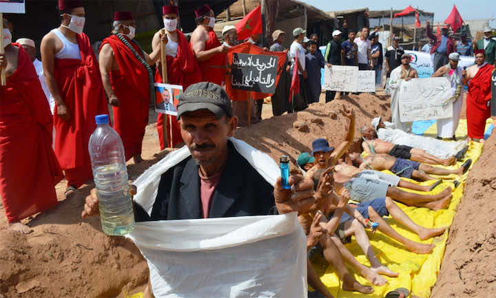 انزكان.. تجار يحتجون وسط مقبرة بالأكفان ويهددون بإحراق أنفسهم- فيديو